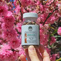 Immunity Boost capsules in front of a cherry blossom tree